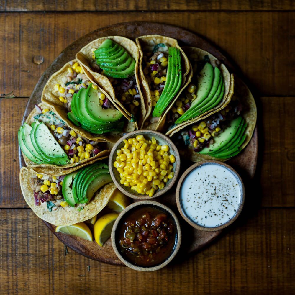 Ein Teller mit Tacos und drei kleinen Schüsseln mit extras
